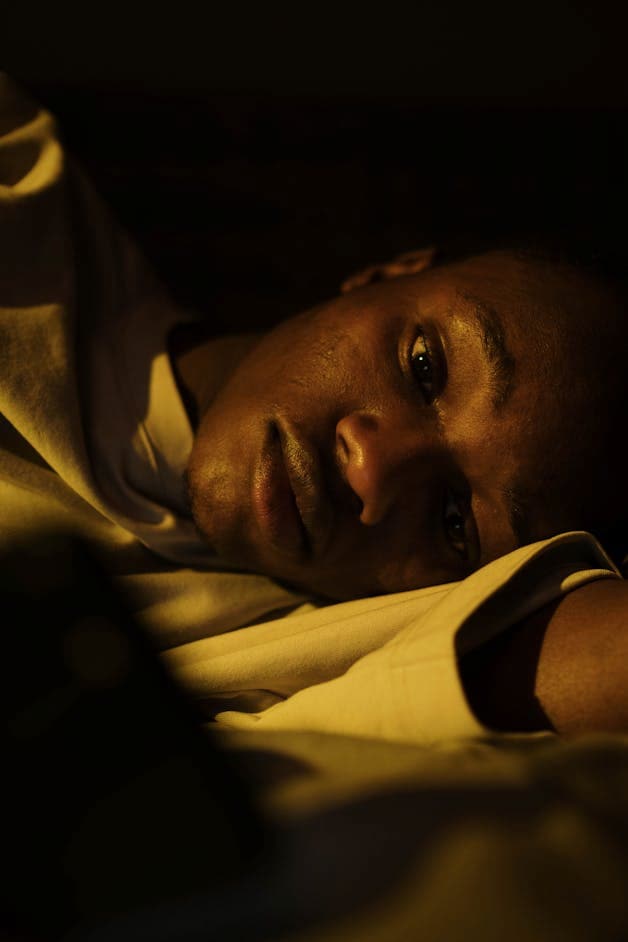 Person lying awake in bed at night representing Americas sleep crisis and chronic sleep deprivation