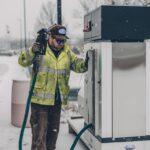 Person filling up their car at a gas station as prices surge across America following the US-Israel strikes on Iran in February 2026 pushing gas from $2.98 to $3.93 a gallon