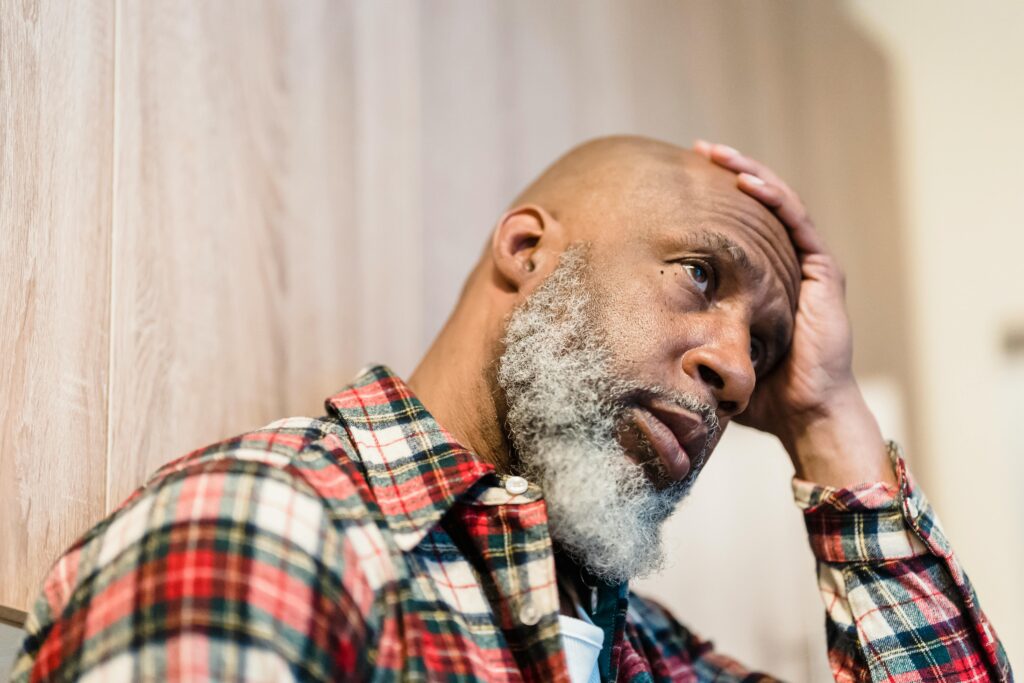 Middle-aged man sitting with head in hands representing the 530,000 American families who file for medical bankruptcy every year — most of them with health insurance at the time their bills arrived