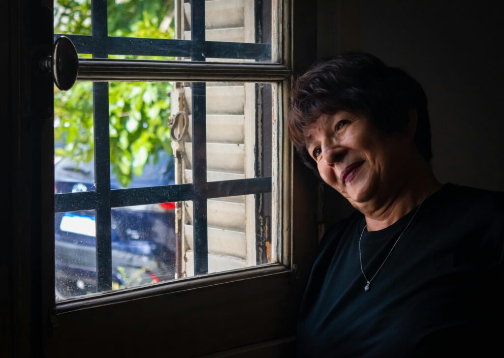 Older woman sitting alone by a window representing Americans aged 50 to 65 who are too young for Medicare and too expensive for ACA marketplace plans — the most financially exposed group in the 2026 healthcare crisis