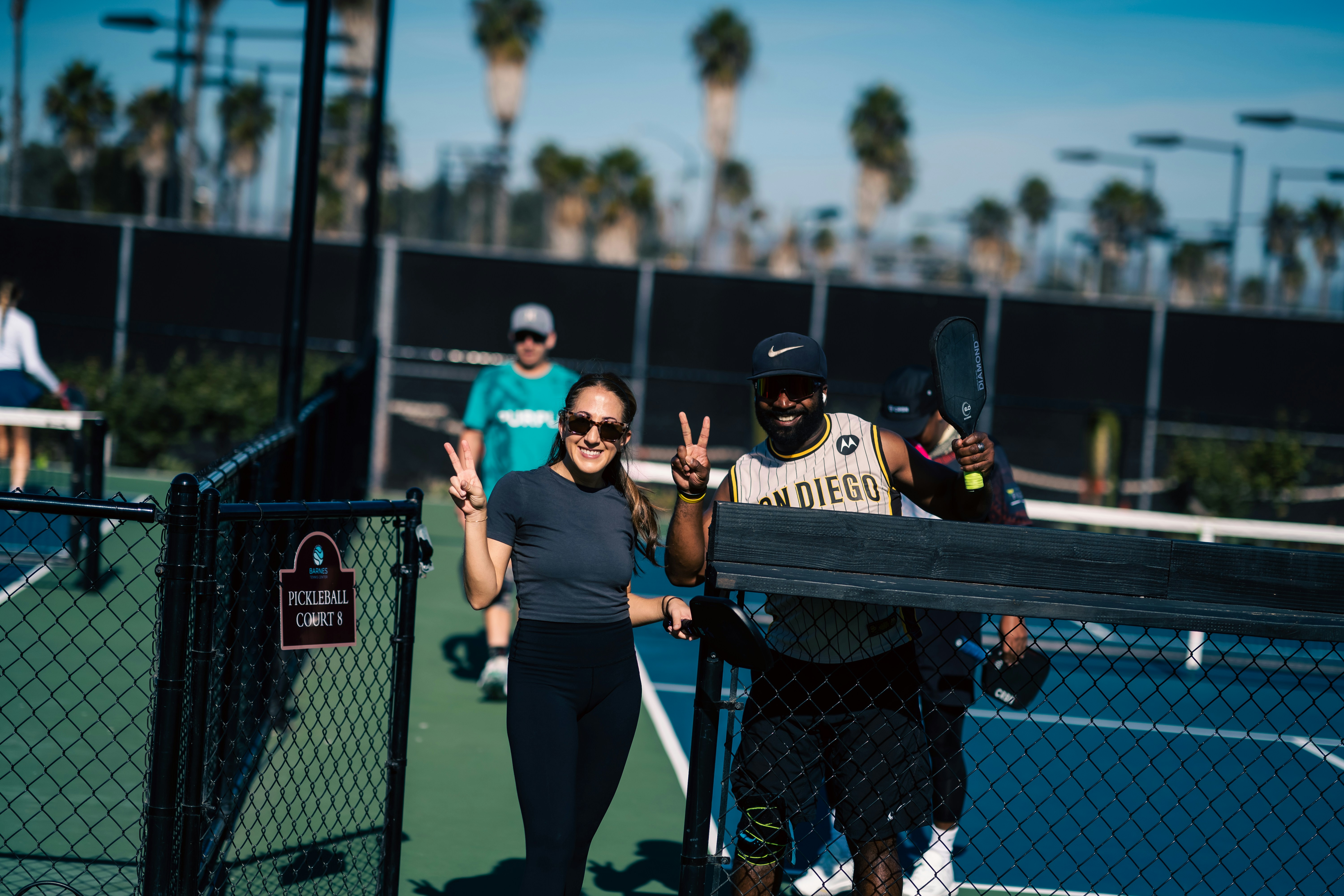 Group of friends laughing while playing pickleball showing social and mental health benefits